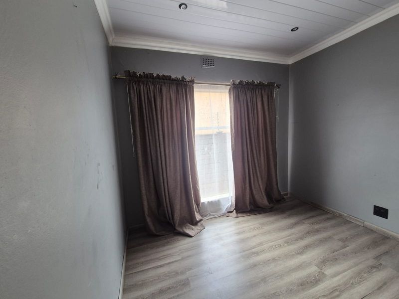 An empty bedroom featuring laminate flooring, a tongue and groove ceiling with recessed lighting, and neutral grey walls.