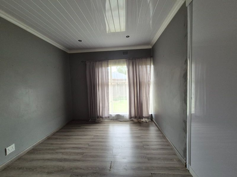 An empty bedroom featuring laminate flooring, built-in wardrobe, and PVC ceiling panels with recessed lighting.