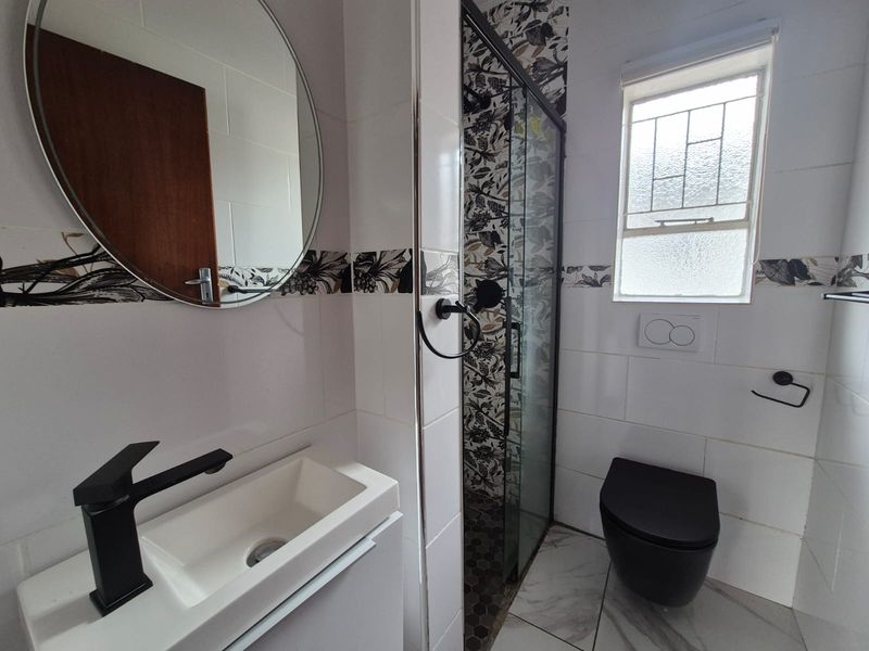 Modern bathroom featuring a sleek vanity basin, black fixtures, a glass-enclosed shower, and contemporary patterned wall tiles.