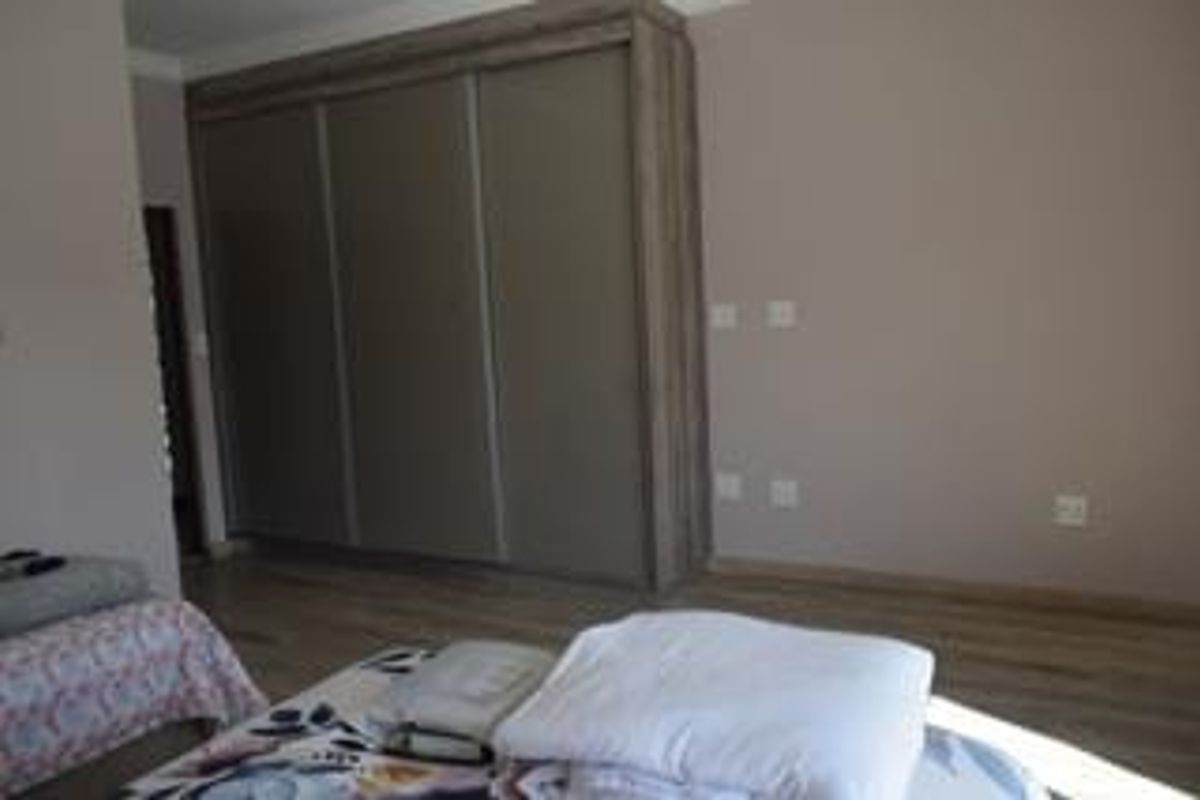 A bedroom featuring a large built-in wardrobe with sliding doors and modern laminate flooring.