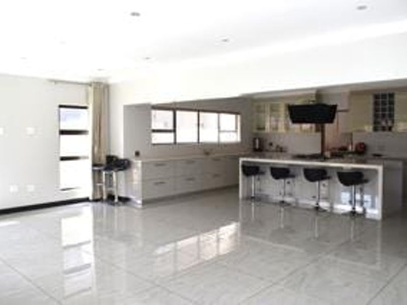 Spacious open-plan living area featuring a modern kitchen with a central island, sleek cabinetry, and polished tiled flooring throughout.