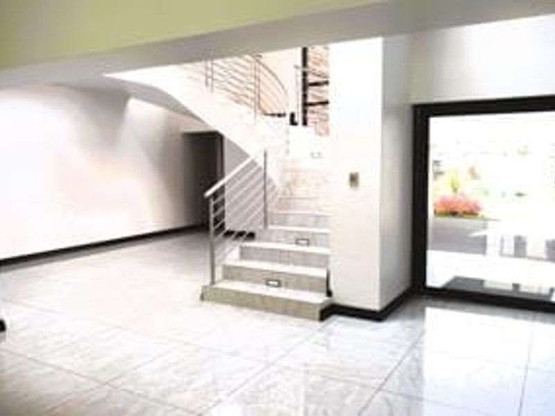 Spacious entrance hall featuring polished tiled flooring, a modern staircase with stainless steel balustrades, and recessed stair lighting leading to the upper level.