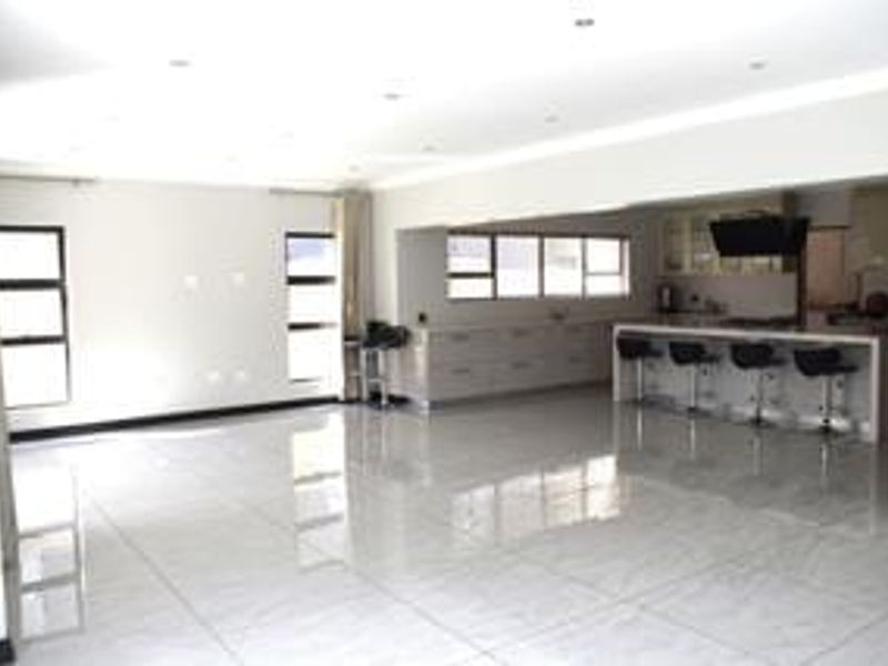 Spacious open-plan living and kitchen area featuring modern tiled flooring, recessed lighting, and a functional kitchen island with built-in cabinetry.