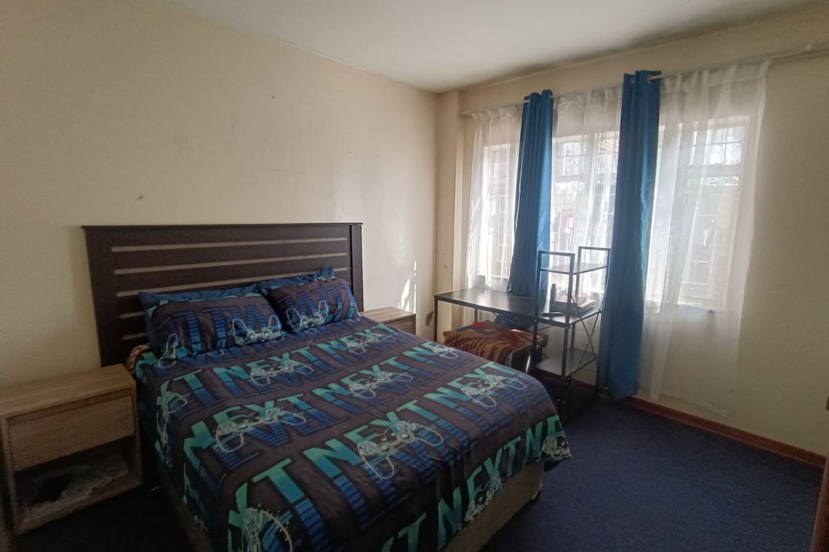 A standard bedroom featuring carpeted flooring and a window with installed curtain rods, providing a functional space with potential for cosmetic updates.