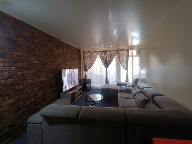 A living room featuring an exposed brick accent wall and access to an outdoor area through a sliding glass door.