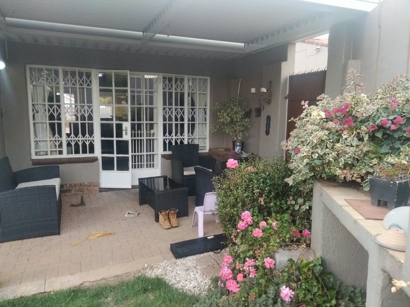 A covered patio area featuring paved flooring and security gates, providing a functional outdoor space for relaxation.