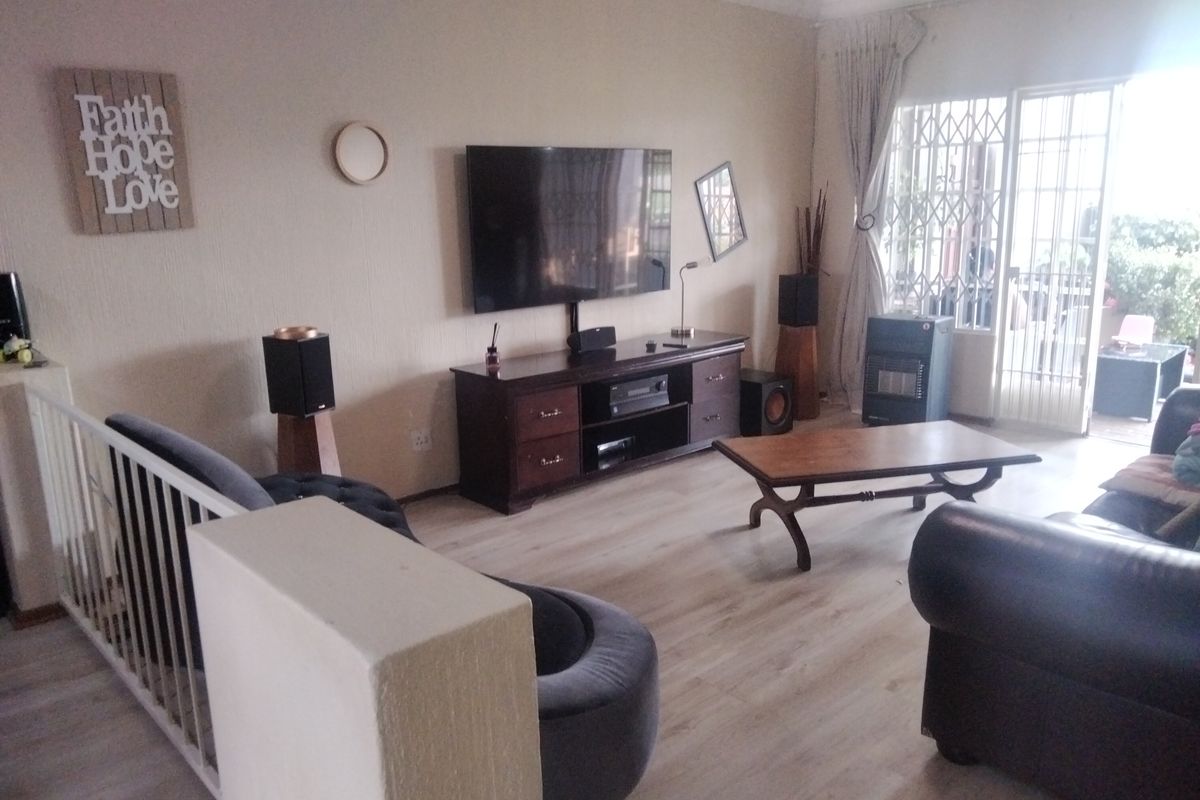 A comfortable living room featuring light-toned laminate flooring, a built-in gas heater, and direct access to an outdoor patio through a secure sliding door.