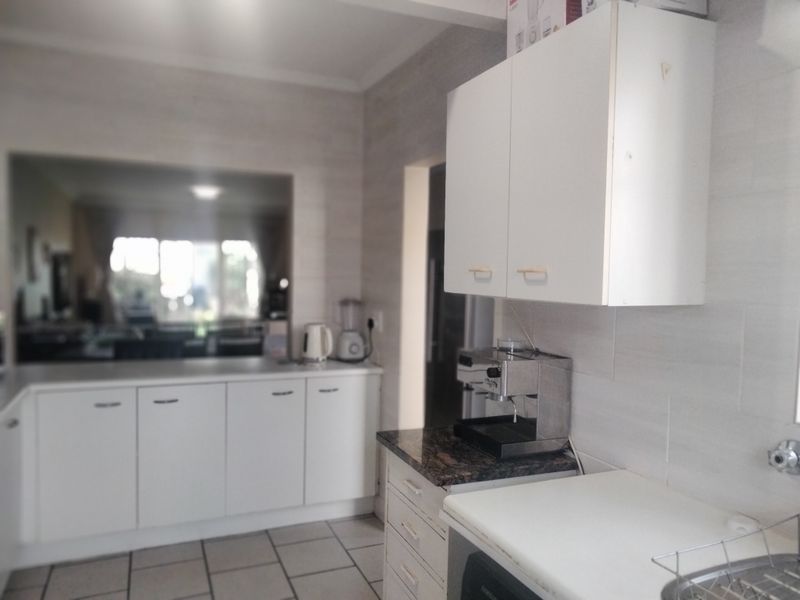 A functional kitchen featuring white built-in cabinetry, granite countertops, and tiled flooring, offering a clean and practical workspace.