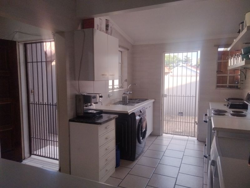 Functional kitchen featuring tiled flooring, built-in cabinetry, and direct access to the exterior via security gates.