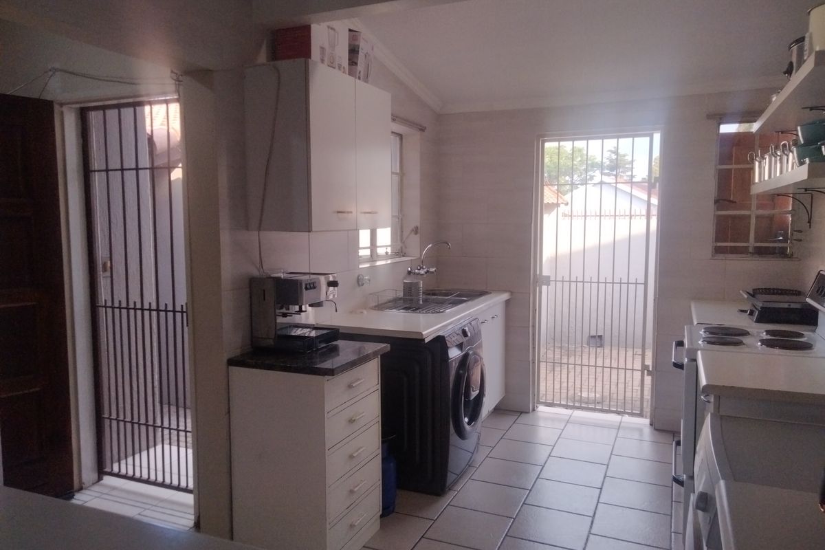 Functional kitchen featuring tiled flooring, built-in cabinetry, and direct access to the exterior via security gates.