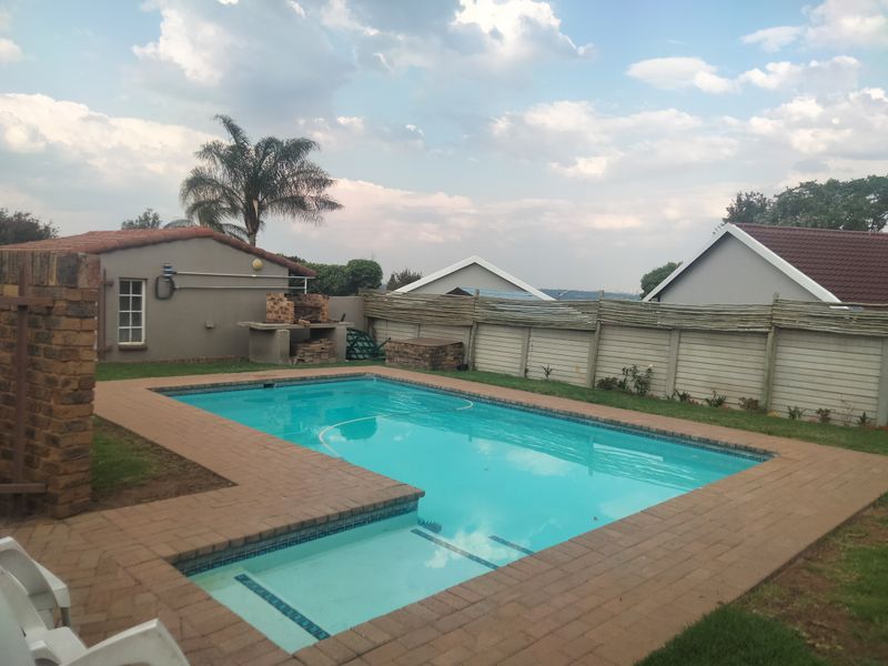 Outdoor pool area featuring a swimming pool with brick paving surround, a built-in braai, and perimeter boundary walling.