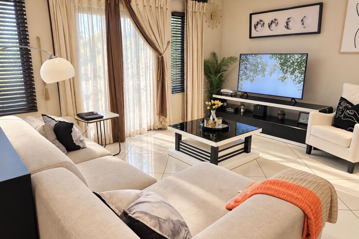A bright and well-maintained living room featuring large sliding glass doors, tiled flooring, and modern window treatments.