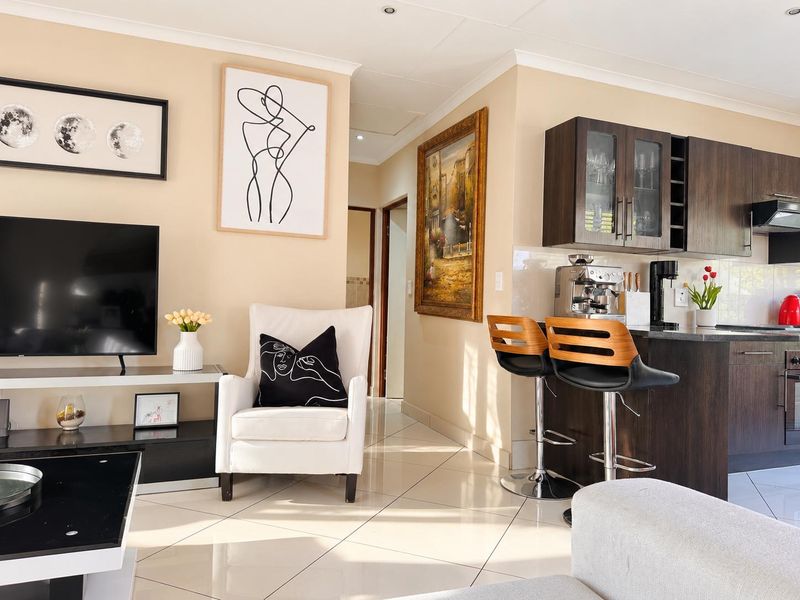 Open-plan living area featuring tiled flooring, recessed lighting, and a modern kitchen with dark wood cabinetry and integrated appliances.