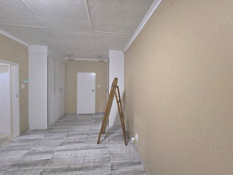 An empty bedroom featuring neutral wall finishes, built-in cupboards, and modern tiled flooring, providing a clean and versatile space.