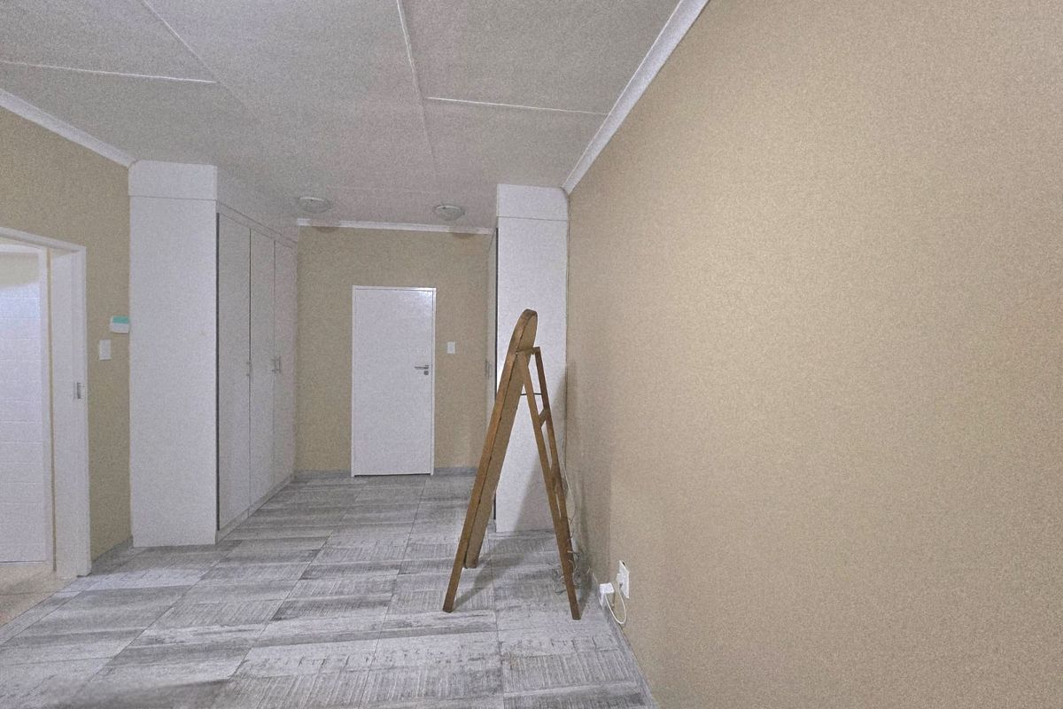 An empty bedroom featuring neutral wall finishes, built-in cupboards, and modern tiled flooring, providing a clean and versatile space.