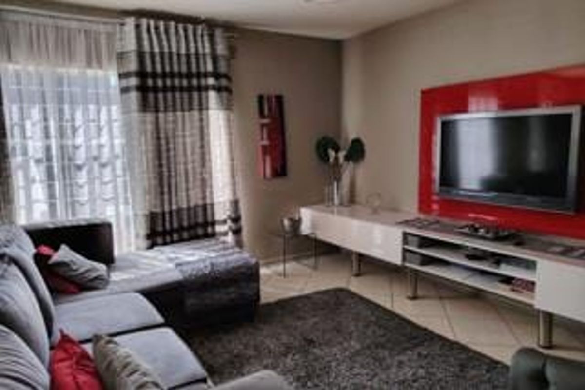 A comfortable living room featuring tiled flooring, a built-in media console, and a sliding glass door providing natural light.