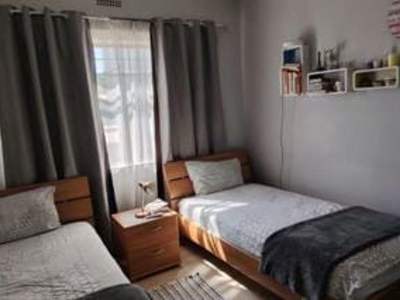 A functional bedroom featuring neutral wall finishes and window treatments, providing a comfortable space for rest.