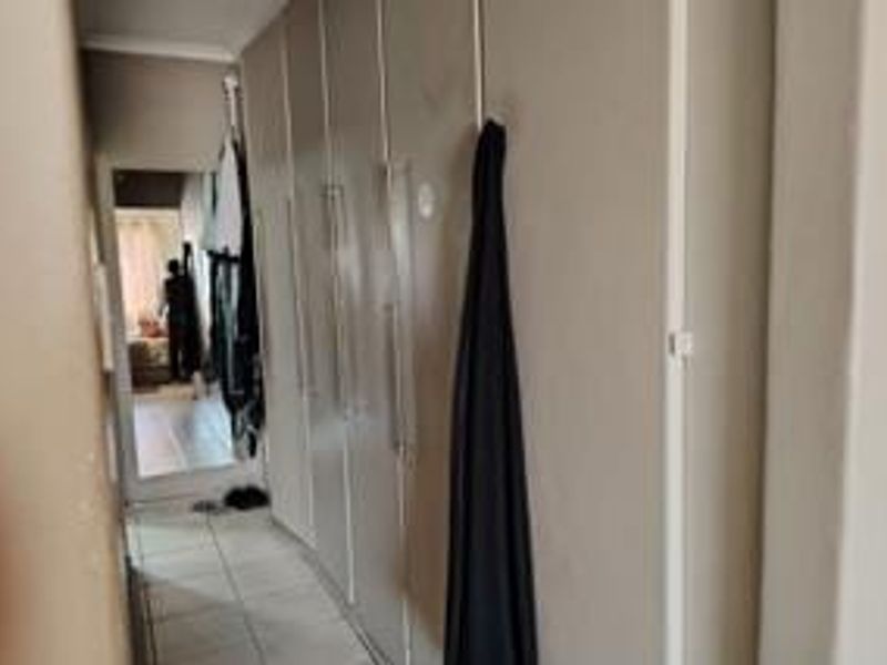 A hallway featuring built-in cupboards and tiled flooring, providing functional storage space within the townhouse.