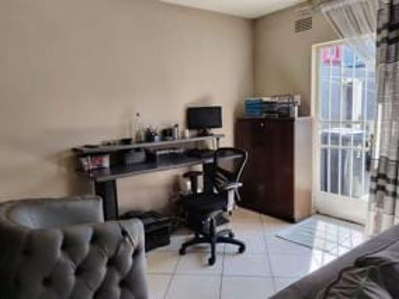 A functional home office space featuring tiled flooring and direct access to an outdoor area through a glass panel door.