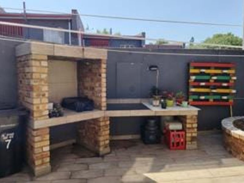 Outdoor patio area featuring a built-in brick braai, tiled prep surface, and a raised brick planter, providing a functional space for outdoor entertaining.