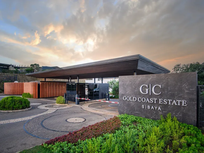 The secure entrance gatehouse of Gold Coast Estate in Sibaya, featuring modern architectural design, paved driveway, and professional landscaping.