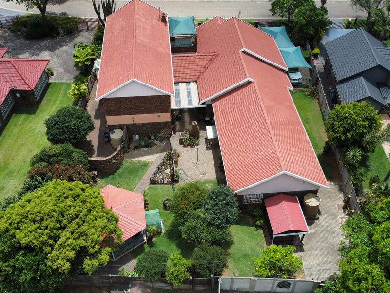 Aerial view of a residential property featuring a tiled roof, landscaped garden, swimming pool, and paved outdoor areas.