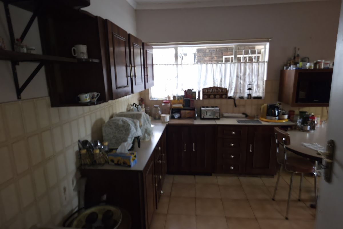 A functional kitchen featuring traditional wooden cabinetry, tiled backsplash, and tiled flooring, offering a classic layout with ample storage space.