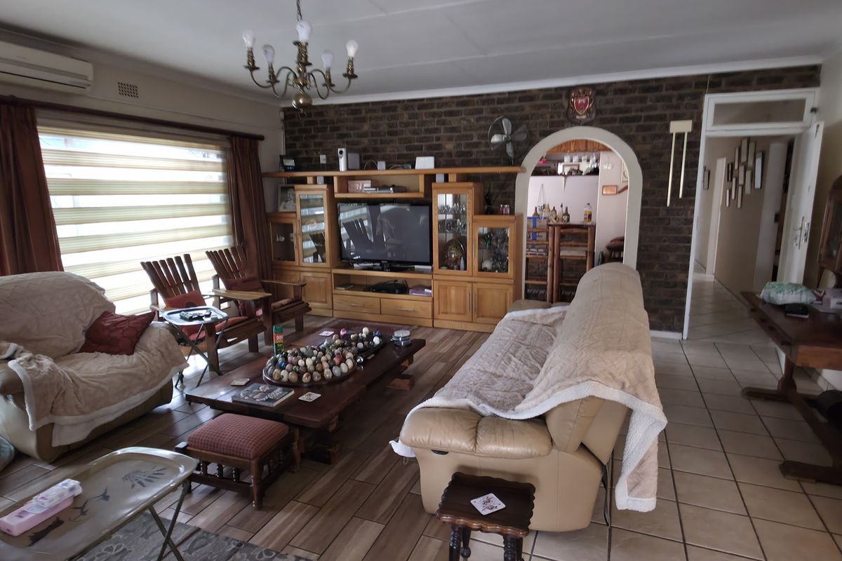 Spacious living room featuring an exposed brick wall, tiled flooring, and a split-system air conditioner, with an arched entryway leading to adjacent areas.