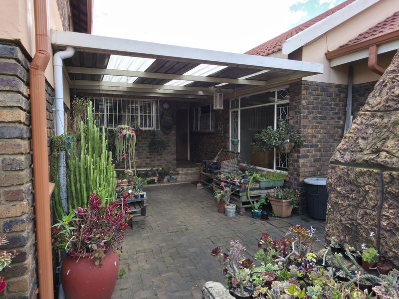 A covered outdoor patio area featuring brick paving, a stone-clad chimney, and translucent roofing, providing a functional space for outdoor living.
