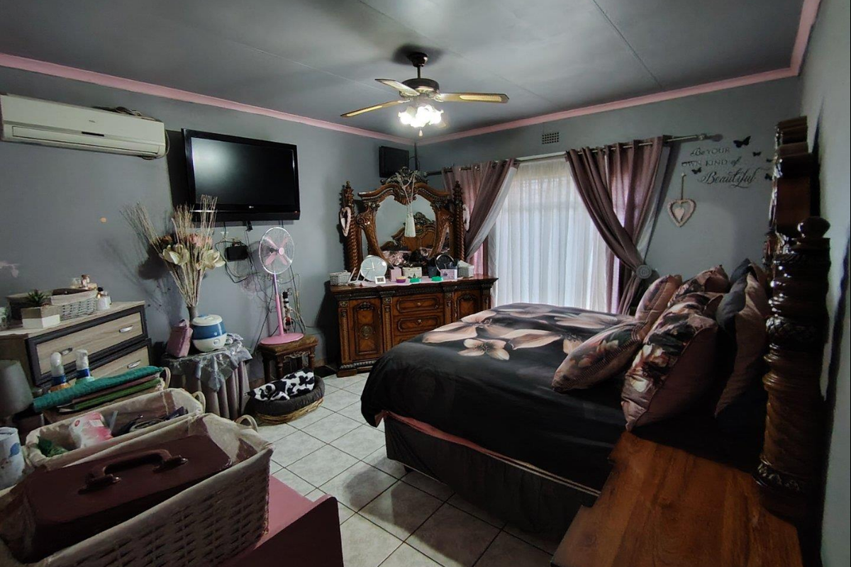 A bedroom featuring tiled flooring, a ceiling fan, and a wall-mounted air conditioning unit.