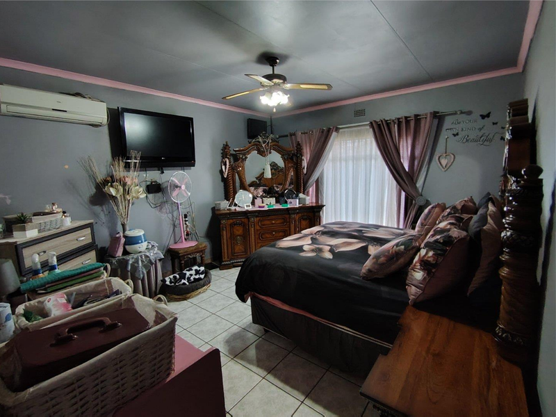 A bedroom featuring tiled flooring, a ceiling fan, and a wall-mounted air conditioning unit.