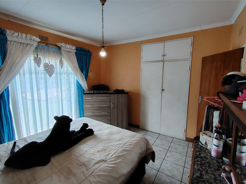 A bedroom featuring tiled flooring, built-in cupboards, and a central pendant light fixture.