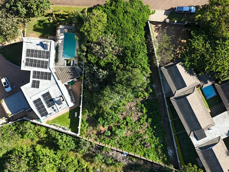 Aerial view of a residential property featuring a main dwelling with solar panels, a swimming pool, and landscaped grounds.