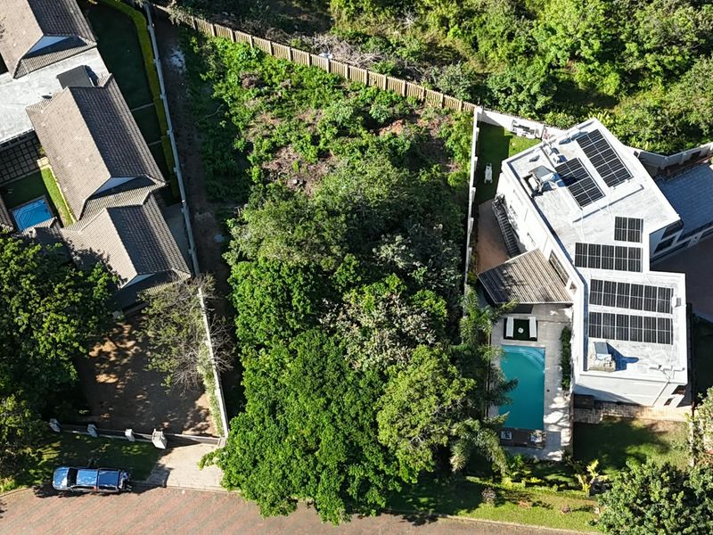 Aerial view of a residential property featuring a swimming pool, solar panel installation, and established garden surroundings.