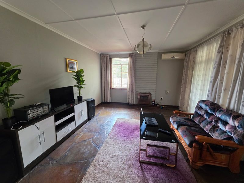 A living room featuring unique stone flooring, a brick fireplace feature wall, and a wall-mounted air conditioning unit.