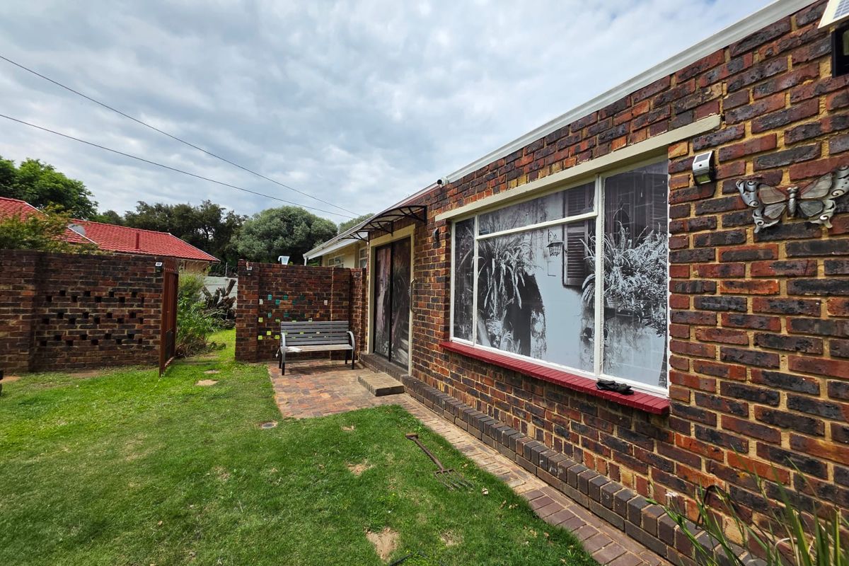 Rear exterior view of the property featuring a face brick facade, paved patio area, and enclosed garden space.