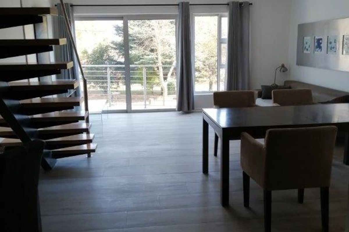 Spacious living area featuring a modern spiral staircase, large sliding glass doors leading to a balcony, and contemporary tiled flooring.