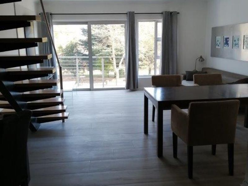 Spacious living area featuring a modern spiral staircase, large sliding glass doors leading to a balcony, and contemporary tiled flooring.