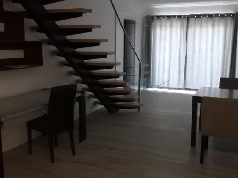 Open plan living area featuring a modern floating staircase, laminate flooring, and large sliding glass doors leading to an outdoor space.