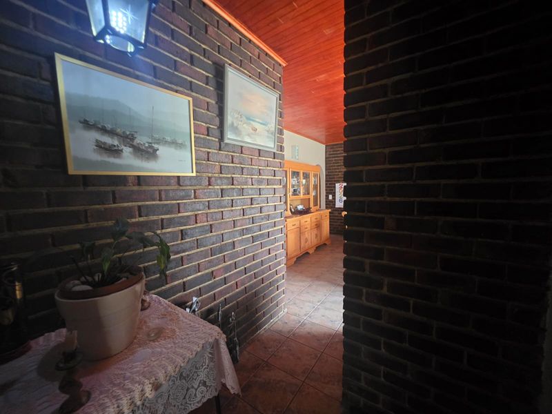 A hallway featuring exposed brick walls, ceramic floor tiles, and a warm timber tongue and groove ceiling.