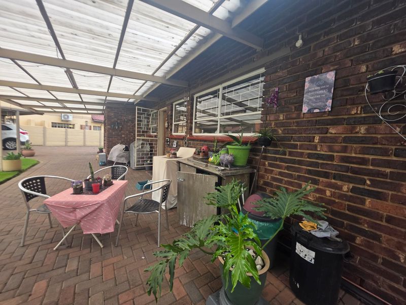 A covered outdoor patio area featuring brick walls, paved flooring, and a translucent roof structure, providing a functional space for outdoor living.