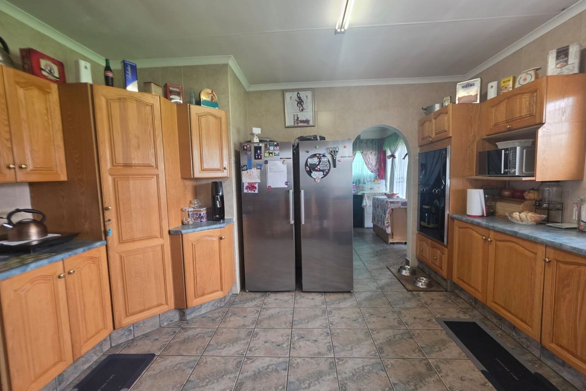 A functional kitchen featuring traditional wooden cabinetry, tiled flooring, and a built-in oven, offering a classic layout with potential for modern updates.