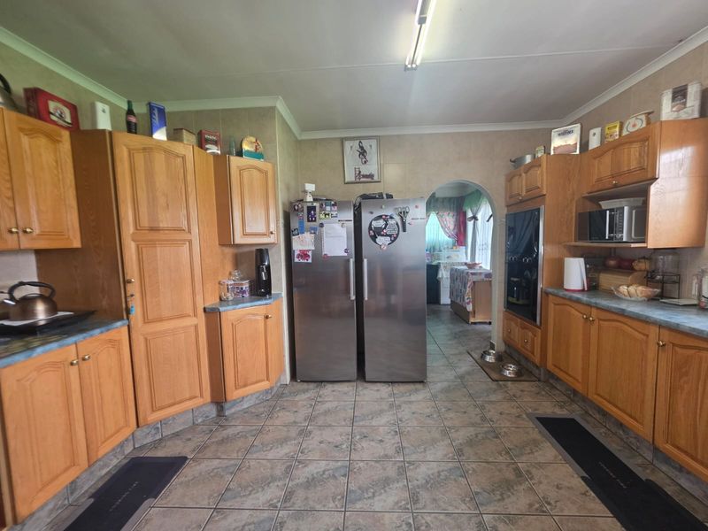 A functional kitchen featuring traditional wooden cabinetry, tiled flooring, and a built-in oven, offering a classic layout with potential for modern updates.