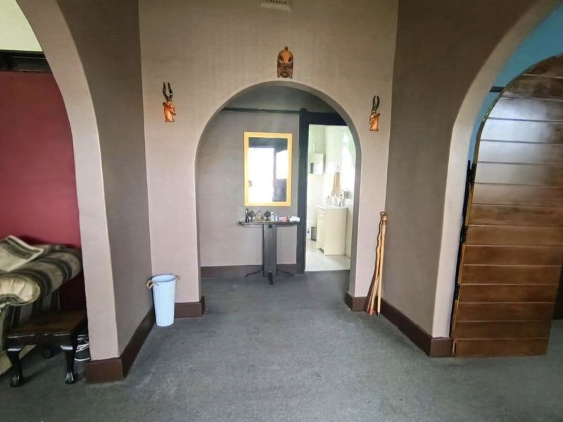 A central hallway featuring distinctive arched architectural openings connecting to adjacent living spaces and a bathroom.