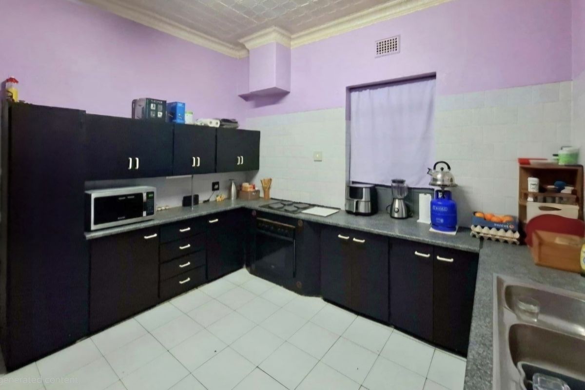 A functional kitchen featuring dark built-in cabinetry, laminate countertops, a built-in oven with hob, and a double bowl sink with tiled backsplash.