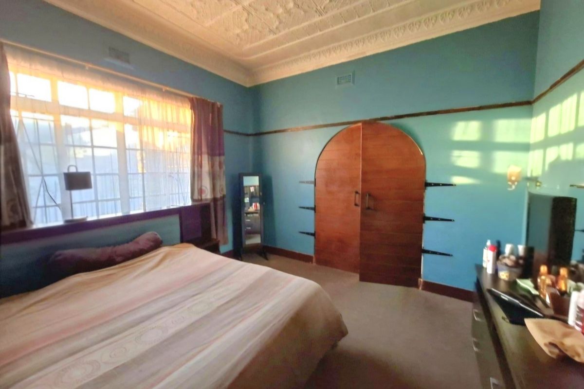 Spacious bedroom featuring a classic ornate pressed metal ceiling, picture rails, and a distinctive arched built-in wardrobe.