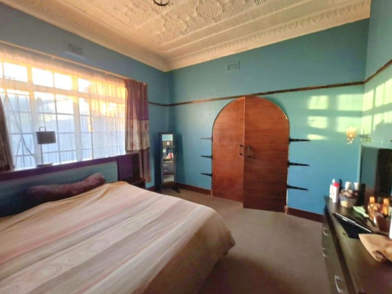 Spacious bedroom featuring a classic ornate pressed metal ceiling, picture rails, and a distinctive arched built-in wardrobe.