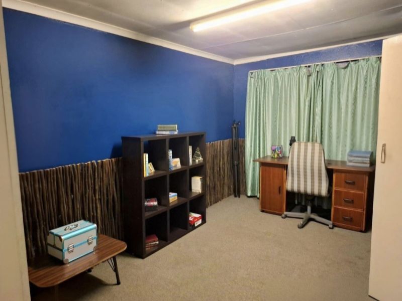 A bedroom featuring blue painted walls with decorative wood-effect paneling, fitted carpet, and a built-in cupboard.