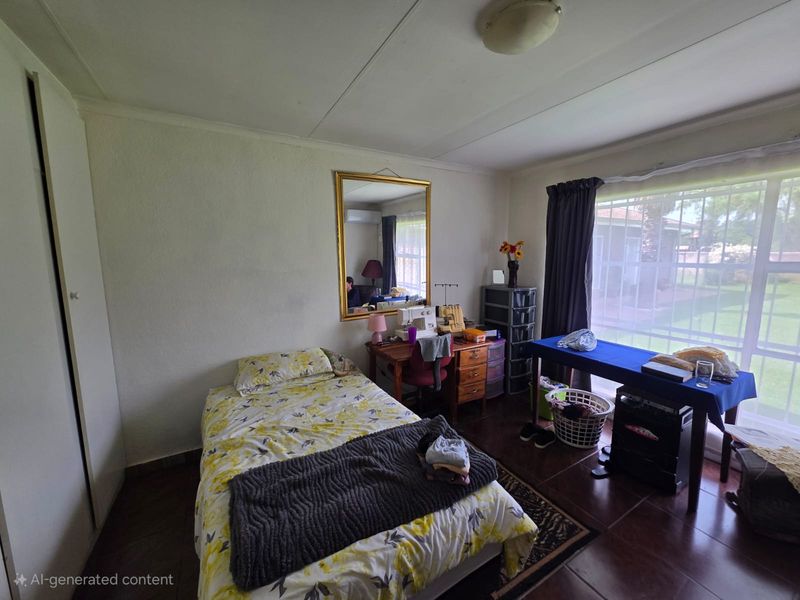 A functional bedroom featuring tiled flooring, a built-in cupboard, and large windows fitted with security bars.