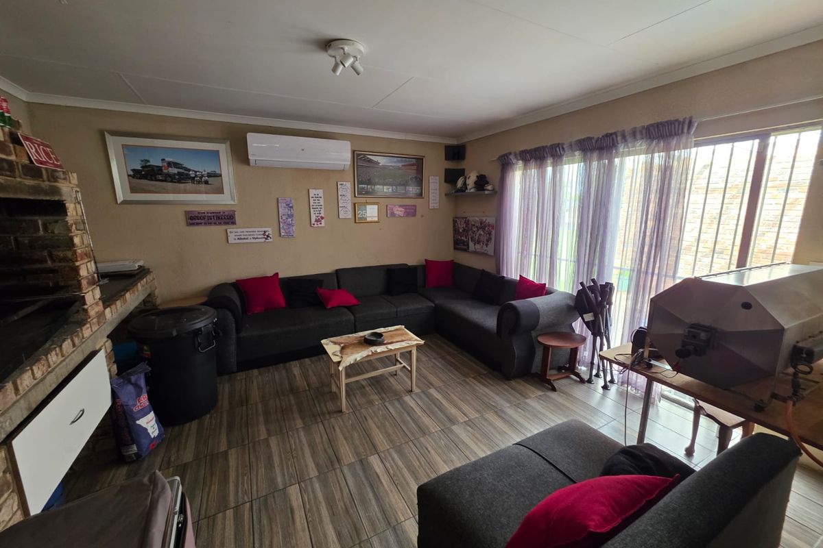 A living room featuring tiled flooring, a built-in brick fireplace, and a wall-mounted air conditioning unit with access to an outdoor area via sliding doors.